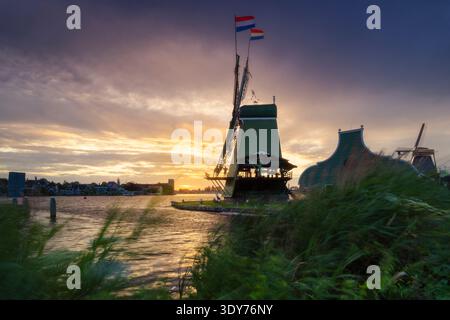 Sunset view of a windmill with flags at Zaanse Schans during summer in North Holland Stock Photo