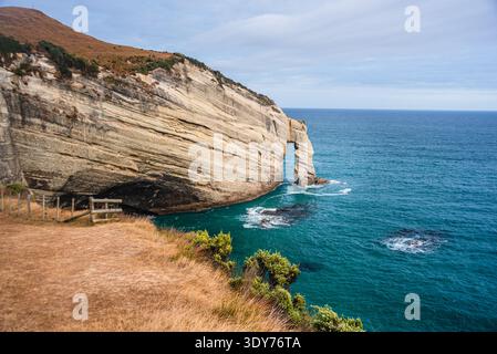 Sedimentary rock formations rise over turquoise waters at coastal area in New Zealand near Cape Farewell Stock Photo