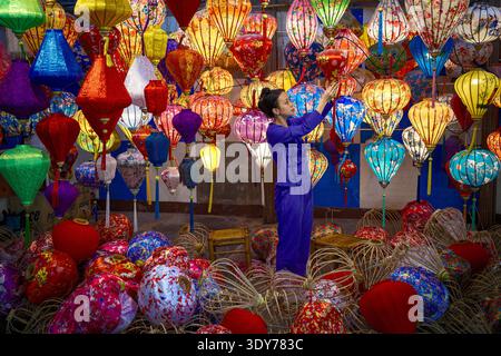 Woman arranges colorful lanterns in a workshop in Vietnam during the day showcasing traditional craftsmanship Stock Photo