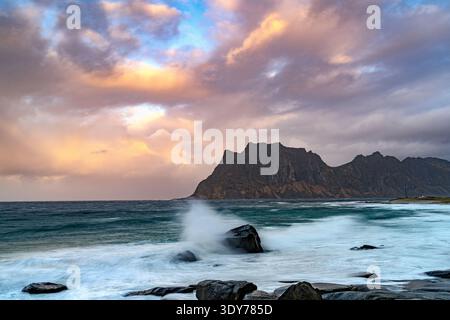 Sunset over rocky shore with waves in Norwegian Sea at Uttakleiv in Lofoten Islands Norway Stock Photo
