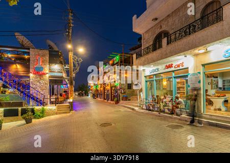 View of shops and tavernas in Piskopiano village as lights turn on during dusk in Crete, Greece Stock Photo