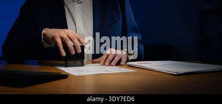 businessman stamping documents on the table in dark office. copy space Stock Photo