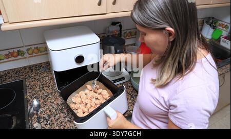Woman cooking dumplings in an air fryer in a modern kitchen  Stock Photo