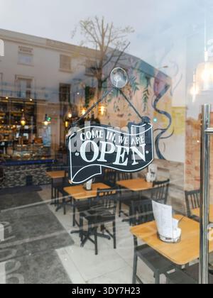 Open sign hanging on glass door of a modern cafe restaurant interior Stock Photo
