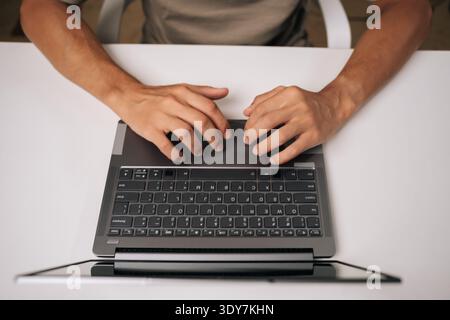Top view of programmer hands typing complex code on laptop keyboard, revealing intense concentration during software engineering workflow. Stock Photo