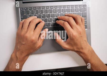 Top view of programmer male typing code on laptop keyboard, showcasing process of software development and coding expertise, close-up. Stock Photo