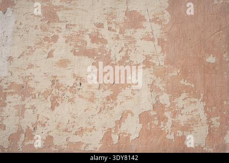 Old pink stucco wall texture with peeling paint and weathered concrete surface Stock Photo
