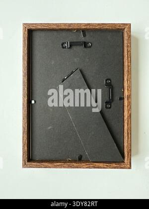 Wooden picture frame back with hangers on light surface, ideal for art display or home decor.. Mobile photo Stock Photo