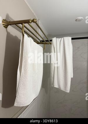 Towels neatly folded on brass rack in bathroom with marble wall background. Mobile photo Stock Photo