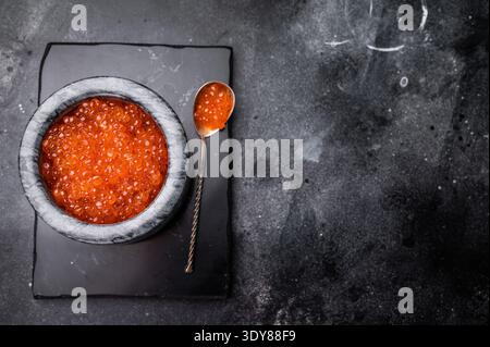 Exquisite salmon roe, vibrant and rich, ideal for adding a touch of elegance to your culinary creations. black background. top view. Stock Photo