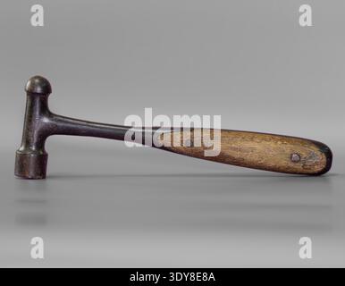 An old hammer with a worn wooden handle placed on a simple background, highlighting the character and history of a traditional hand tool. Stock Photo