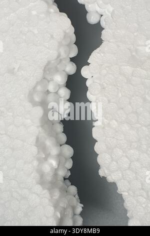 broken white styrofoam pieces isolated grey background, damaged expanded polystyrene packaging material with exposed spherical foam beads in macro Stock Photo