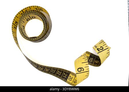 A flexible yellow measuring tape curled up on a white background, perfect for projects requiring precision and accuracy Stock Photo