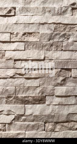 High-quality image of a textured beige stone wall with rustic stacked bricks, perfect for design and architectural projects Stock Photo