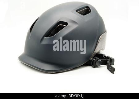 Matte black bicycle helmet on white background, three vents visible, chin strap with buckle, side view, studio lighting Stock Photo