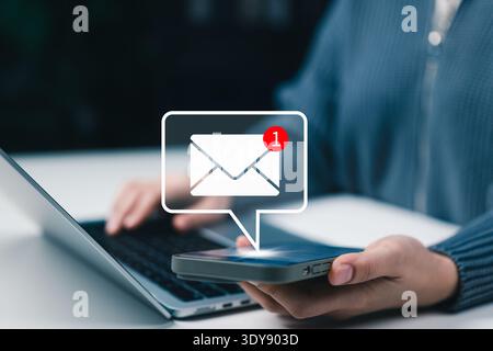 Email notification and online communication concept. User using smartphone receiving new message alert with envelope notification icon while working Stock Photo