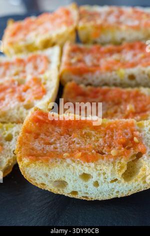 Pan con tomate, in Catalan, pa amb tomàquet, translated informal pantumaca, traditional in Catalan and Valencian kitchens. It is a slice of bread with Stock Photo
