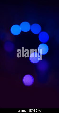Dark background with abstract blue and purple bokeh lights forming a question mark, representing doubt and inquiry Stock Photo