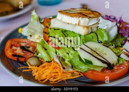 Salad with tomato, cucumber, lettuce, olives, carrots, goat cheese with virgin olive oil and balsamic vinegar. Healthy meal Stock Photo