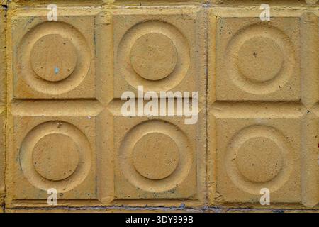 Six yellow textured concrete tiles with raised circular centers arranged in two rows of three, worn surface and small paint flecks Stock Photo