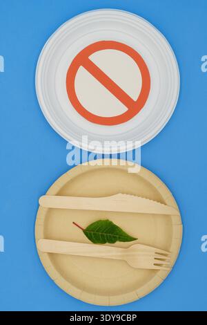 Disposable wooden and plastic plate with forbidden sign on blue background. Eco-friendly materials. No single-use plastics. Save the planet Stock Photo