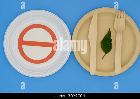 Disposable wooden and plastic plate with forbidden sign on blue background. Eco-friendly materials. No single-use plastics. Save the planet Stock Photo