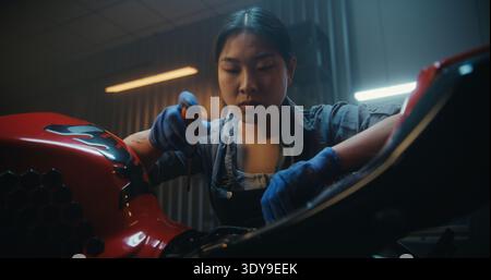 Female Mechanic Beside Partially Disassembled Motorcycle, Tired and Discouraged While Examining Exposed Electronic Components. Attempt Restart Bike Electrical System Failed. Technical Difficulties. Stock Photo