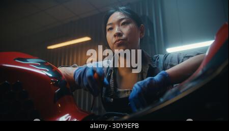 Female Mechanic Beside Partially Disassembled Motorcycle, Tired and Discouraged While Examining Exposed Electronic Components. Attempt Restart Bike Electrical System Failed. Technical Difficulties. Stock Photo