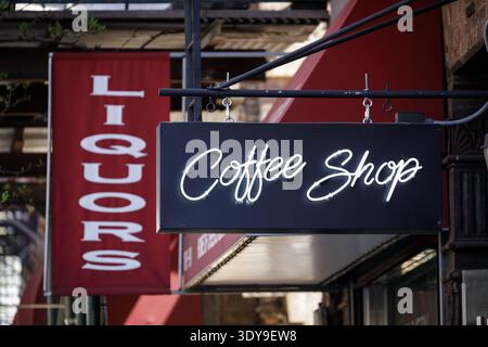 Neon Coffee Shop sign hanging beside a red Liquors banner on a storefront, Chelsea, Manhattan, New York City, USA Stock Photo