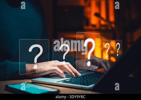 Online customer support and FAQ concept. Close up of businessman hands typing on laptop keyboard with virtual question mark graphics in dark office Stock Photo