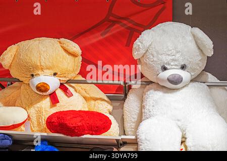 Large soft white and brown teddy bears on a shelf in a toy store Stock Photo