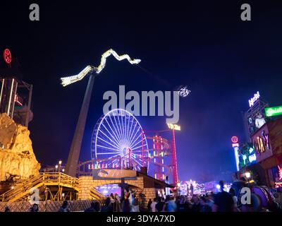 Wiener Prater at night: illuminated Ferris wheel, roller coasters and rides, dramatic lights and crowds, iconic Vienna amusement park. Stock Photo