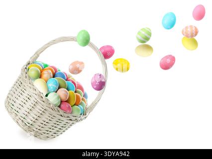 Bright Easter eggs falling into basket on white background Stock Photo