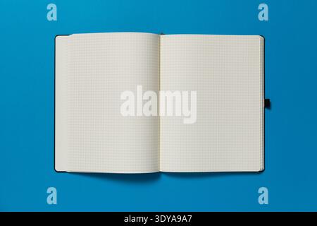 Open notepad on a blue background. The page is blank. Stock Photo