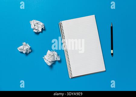 Open spiral notepad on a blue background. The page is blank. Ripped and crumpled pages on the side, Stock Photo