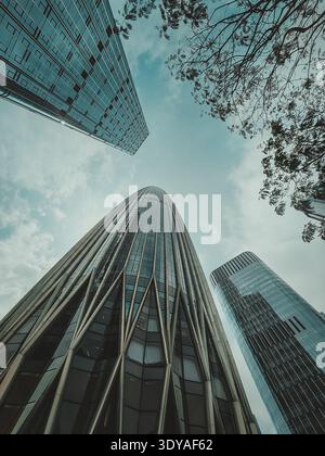 A striking low-angle, close-up photograph of a modern skyscraper in China, showcasing its architectural details against a soft sky, emphasizing its he Stock Photo