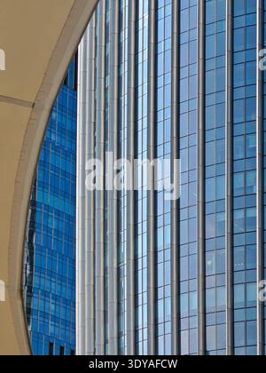 A close-up architectural photograph focusing on the intricate details of a modern skyscraper's facade, featuring a deep blue glass curtain wall reflec Stock Photo