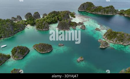 Aerial view of Piaynemo islands in Raja Ampat, Indonesia, with turquoise lagoons, lush green karst islets and stunning tropical seascape, symbol of ex Stock Photo