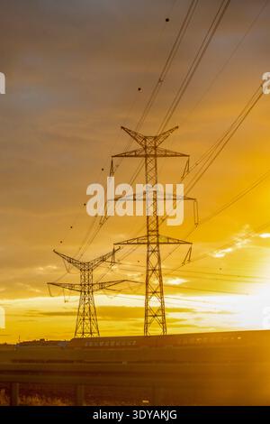 Line of electricity pylons at sunset. Stock Photo