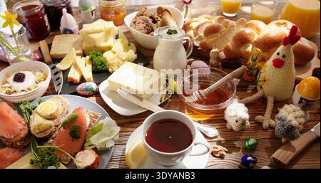 Breakfast spread with bread, cheese, fish, and eggs on a wooden table at a sunny morning Stock Photo
