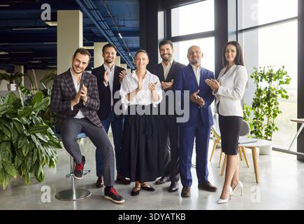 Happy business team clapping hands, smiling on meeting in open space office Stock Photo