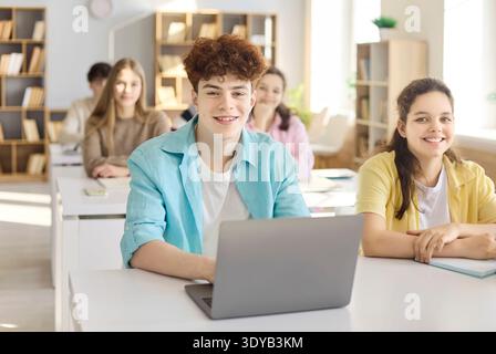 Teen students in class using laptop during lesson, teenagers studying together Stock Photo
