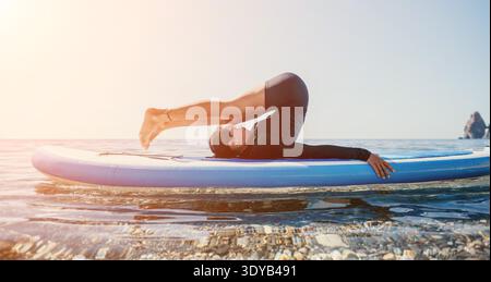 Yoga Paddleboard Ocean Man Practicing Yoga Pose on Paddleboard in Ocean at Sunset Stock Photo