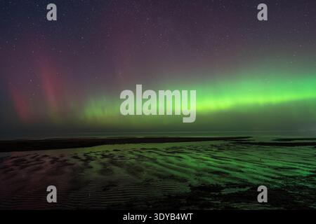 Northern lights above rippled wet sand on the Baltic coast in Lilaste, Latvia Stock Photo