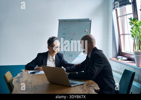 Mature woman and man collaborating in office meeting room Stock Photo