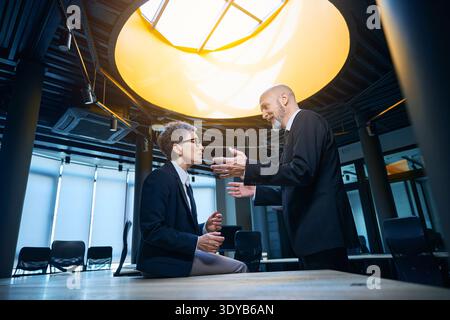 Engaged conversation between man and woman in modern office Stock Photo