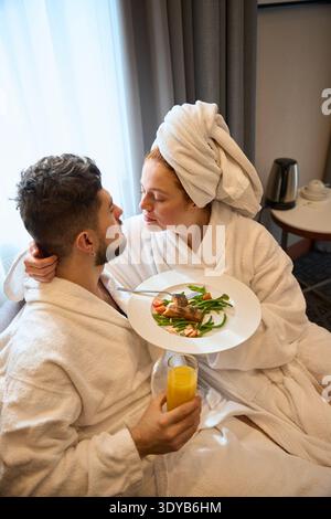 Serene adult couple enjoying breakfast in hotel bedroom Stock Photo