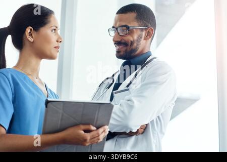 Technology, discussion and doctor with nurse in hospital with planning for surgery schedule together. Tablet, people and team of healthcare employees Stock Photo