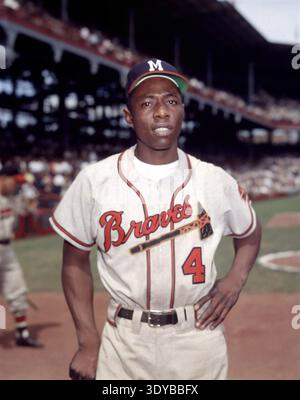 An iconic portrait of Hank Aaron, known as "Hammerin' Hank," from 1954, captured by the Associated Press. He is shown confidently posing in his Milwaukee Braves uniform with the number 4, against the backdrop of a stadium. Stock Photo