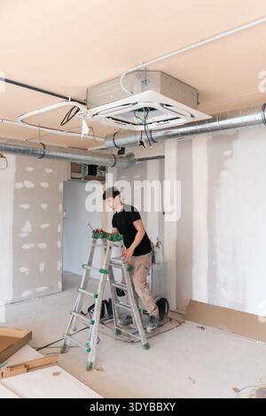 Hvac technician installing air conditioning unit during construction Stock Photo